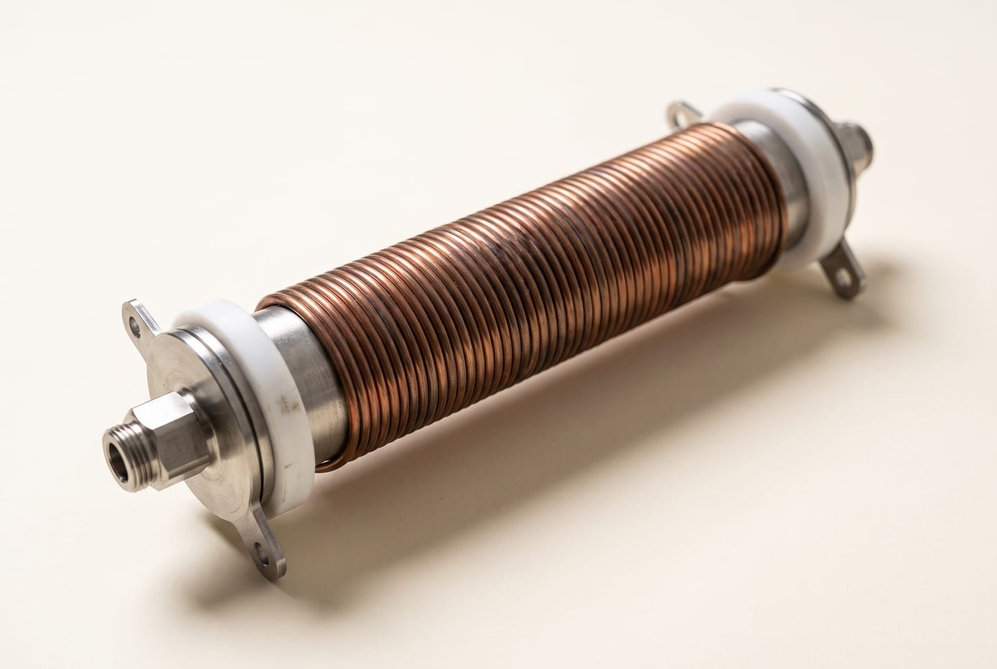The Heylo induction heating element: a copper coil wound around a steel tube, with white PTFE spools and steel fittings at each end